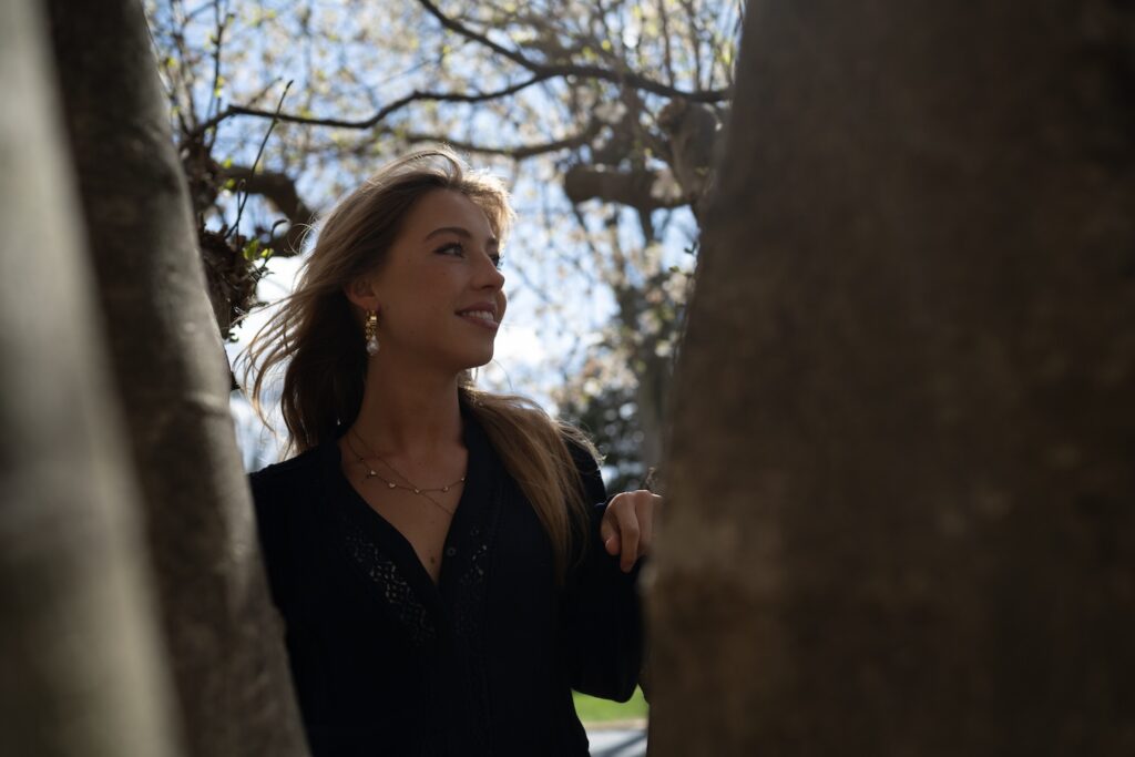 Lineke Spaans is pictured on campus, framed by two trees.