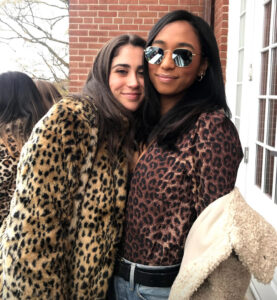 Two women stand next to each other wearing leopard print coats and shirts.