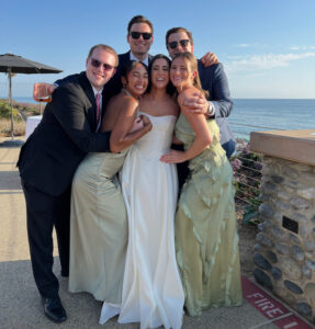 Six people pose at a wedding. The bride is in the center. 