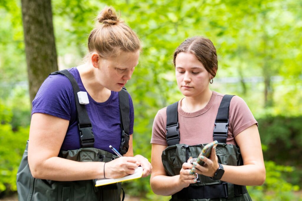 Prof. Christa Kelleher ’08 and Ashley McElroy ’27 compare notes near the Bushkill Creek.