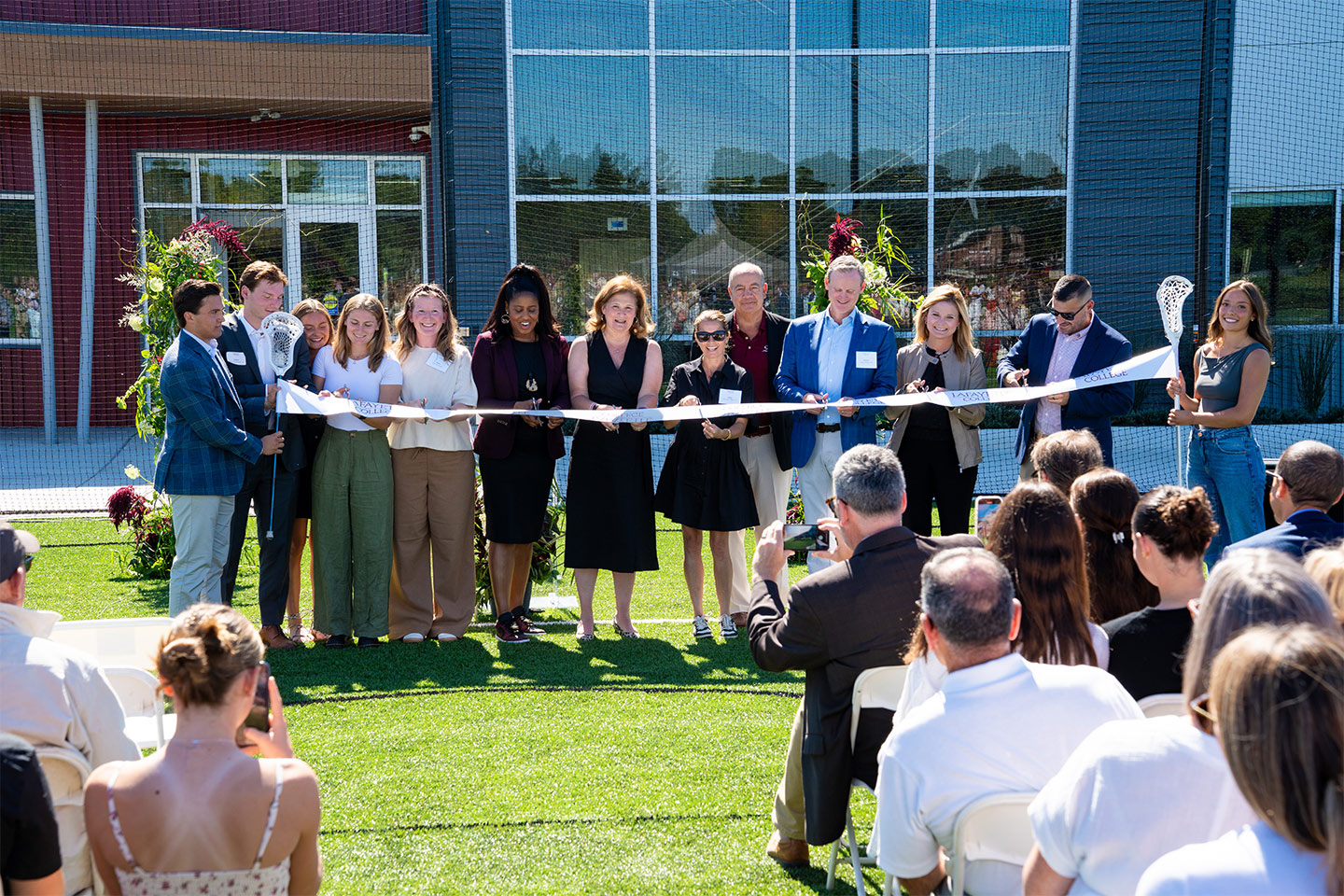 A crowd of Lafayette staff cut the ribbon during the Wallach Sports Performance and Lacrosse Center dedication. President Hurd is in the center.