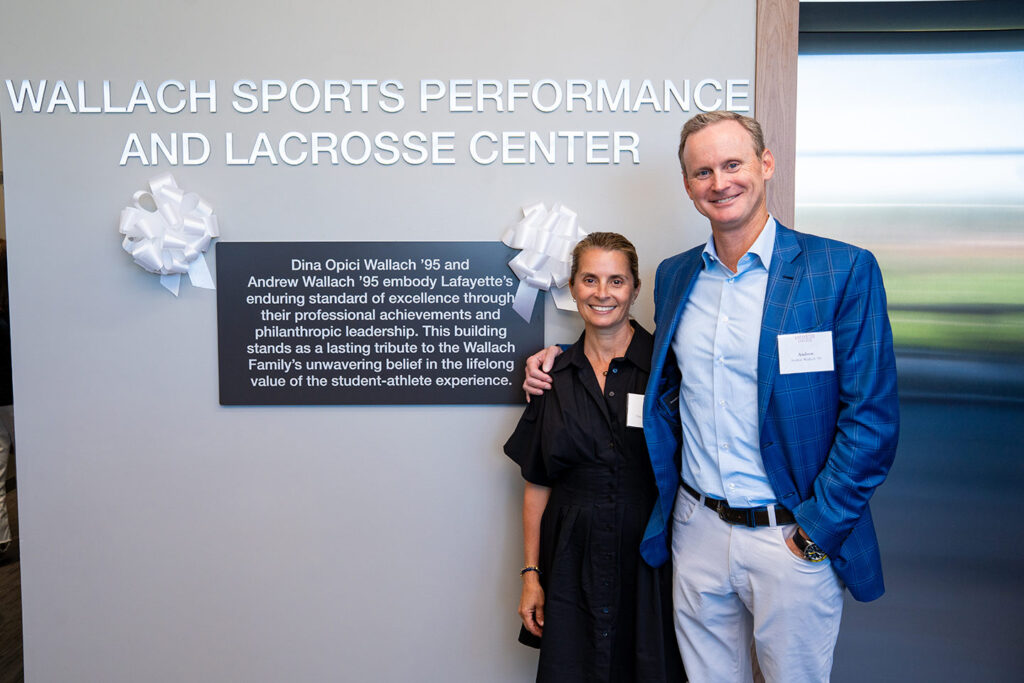 Andrew '95 and Dina Opici Wallach ’95 stand in the lobby of the new Wallach Center near a sign acknowledging their generosity.