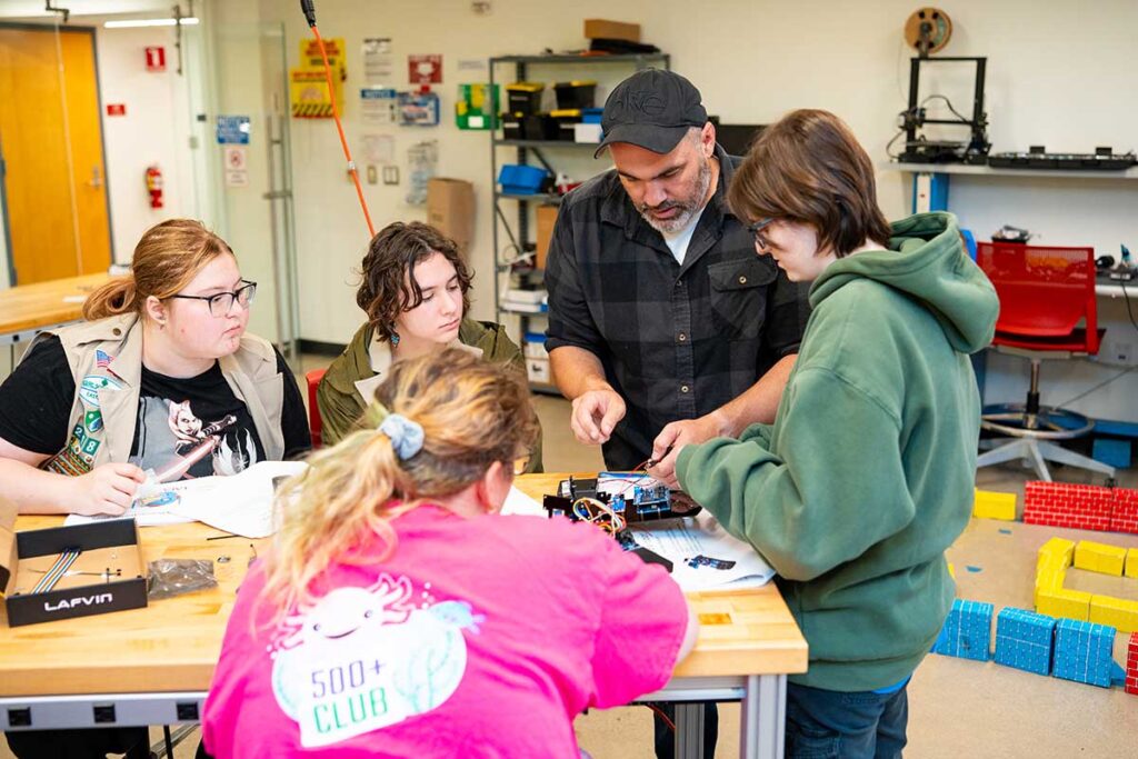 Girl Scouts working on a robotics project with a professor during Girl Scout Badge Day