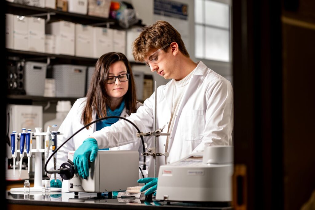 Prof. Melissa Gordon ’11 and Finlay (Finn) Smith '25 look at an instrument in Gordon's lab. 