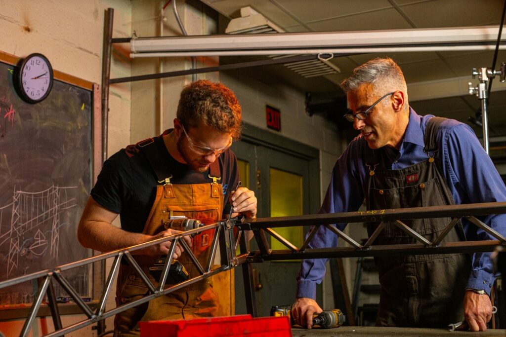 Steve Kurtz and a student examine the joint of a steel bridge
