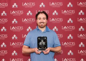 Chris Byrnes holds a Landis award against a Landis background