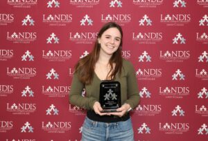 Hailey O' Shea holds an award against a Landis logo background
