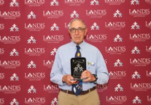 John Squarcia holds a Landis Award in front of a Landis logo background