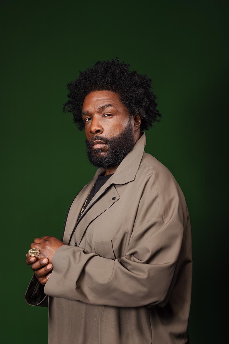 Questlove in front of a green background