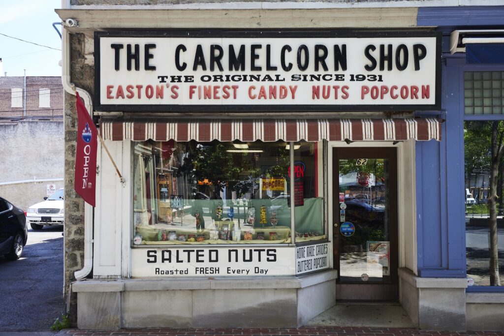 The facade of the Carmelcorn Shop features a main window with a white/black and red awning and signage.