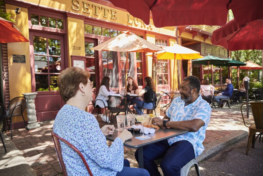 Two diners sit under an umbrella dining al fresco at Sette Luna.