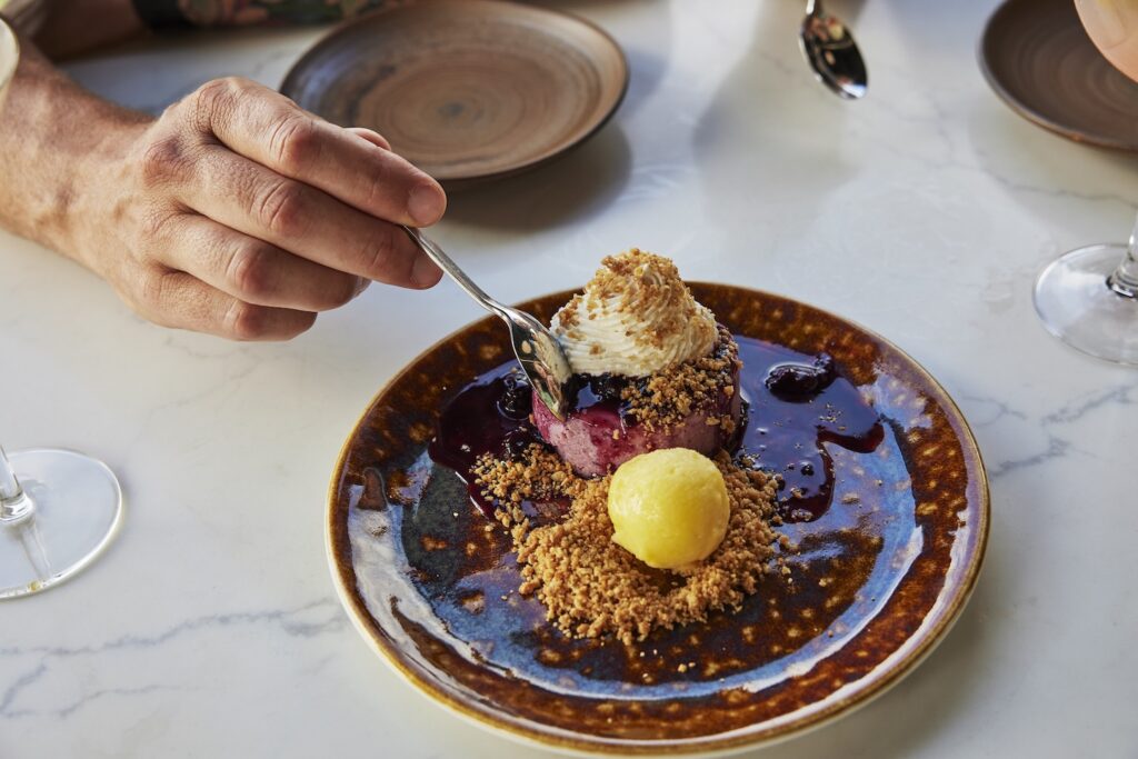A diner dips into a cheesecake on a plate at Thyme.
