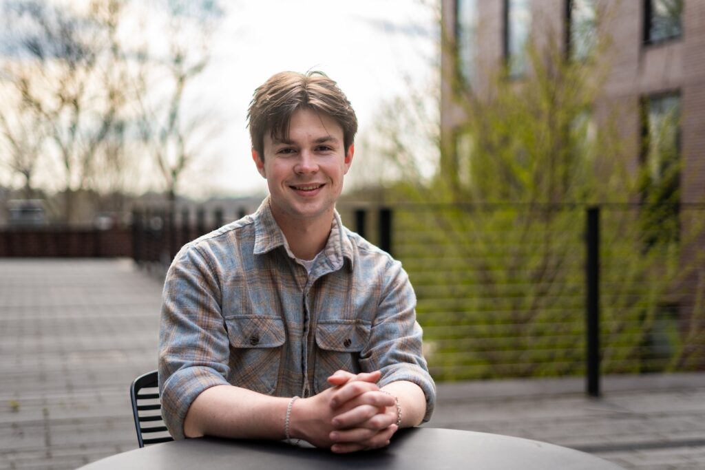 Owen Paschke sits at a table outdoors on the patio beside Rockwell.