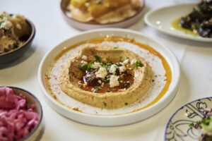 A plate of hummus and several dips and appetizers are shown from Albanesi.