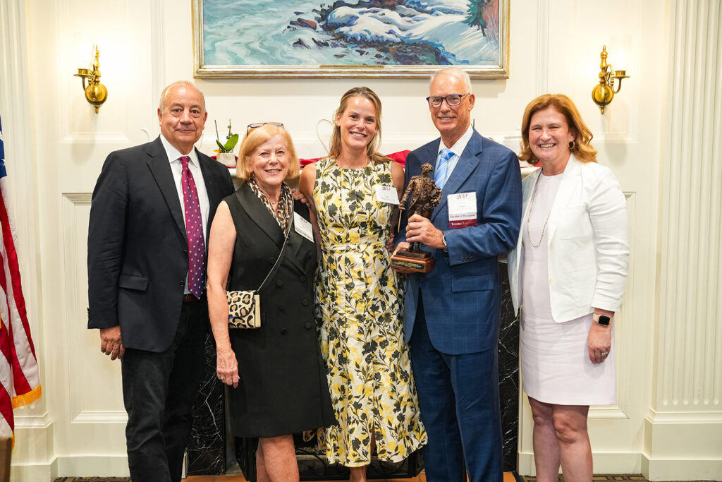 Outgoing Board Chair Bob Sell and President Nicole Hurd pose with three alumni. One alum is holding a mini statue of Marquis de Lafayette.