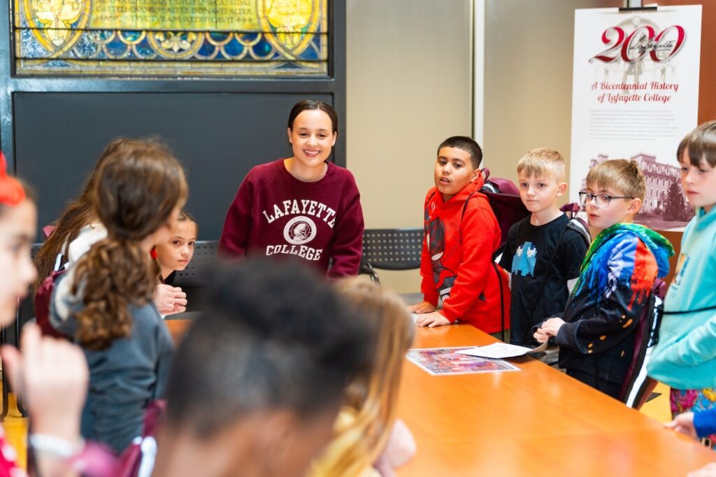A Lafayette student stands in front of a table of fourth graders during their art history trip to Skillman Library.