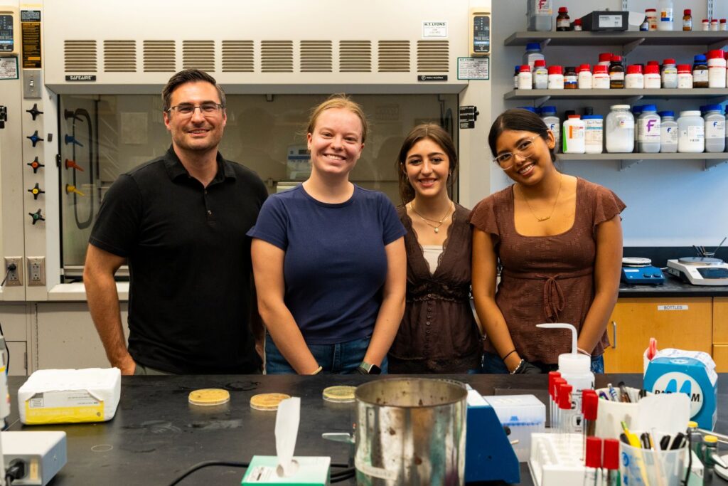 Justin Hines, Lauren Davidson ’27, Melanie Audelo-Riaño ’28, and Christina Vella ’29 pose in a chemistry lab.