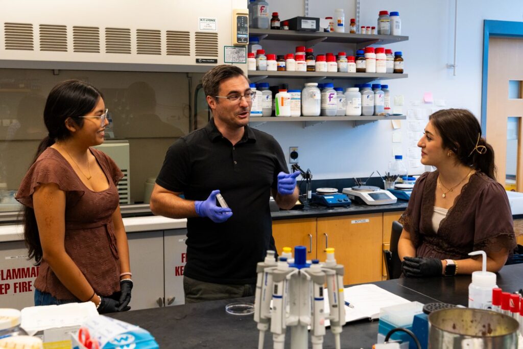 Prof. Justin Hines explains yeast physiology to Melanie Audelo-Riaño ’28, and Christina Vella ’29. (Photo | JaQuan Alston)