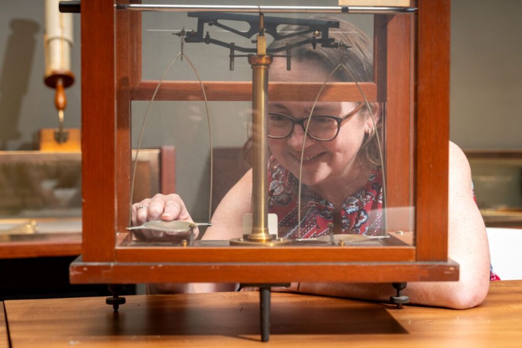 Jenn Stroud Rossmann inspects a vintage mass balance, part of Engineering Artifacts: Past, Present, & Future exhibit at Kirby Art Study Center, Room 109 in Williams Center for the Arts. (Photo | JaQuan Alston)