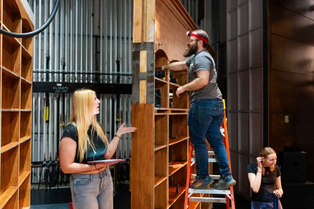 Carly Rodrigues '27 assists Alexander Owens, adjunct professor of theater and production manager/technical director, in building the set for Between the Lines. | Photo by JaQuan Alston
