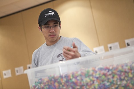 Zhuo Wen Wu '11 puts his hand in the tub of beads representing a fraction of the people killed during the Holocaust.