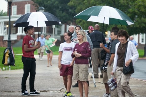 New students and parents wait in the rain to unload their cars.