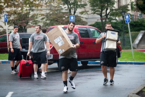 Members of the football team help new students unload their cars.