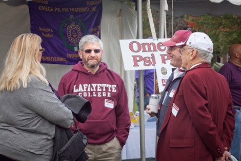 Michael Spinner '77, center, greets other alumni at the Omega Psi Phi tent.