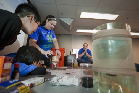 Stacey Dorn '12, center, pours dirty water into a team's water filter as Hannah Greisbach '13 watches.