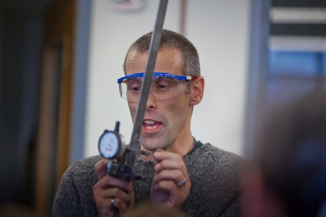 Stephen Kurtz, associate professor of civil and environmental engineering, shows the students how to put a band of steel through a stress test.
