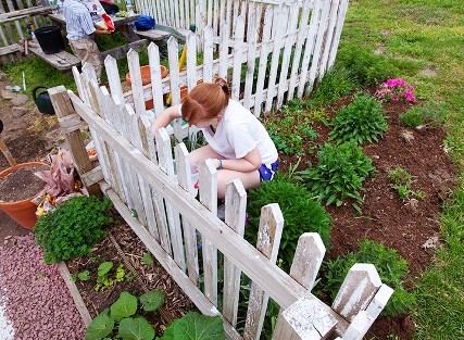Allie Scoular '15 paints the fence that surrounds the West Ward Neighborhood Partnership's community garden at 5th and Ferry streets.