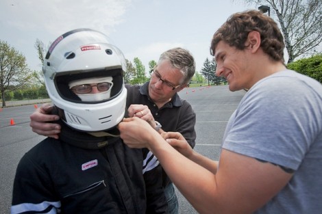 Shane Chalupa ’12, right, and Scott Hummel, professor of mechanical engineering, help Nicholas Moneta '12 with his helmet.  