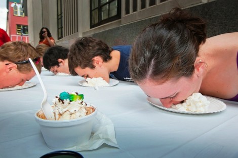 Students try to get the bubble gum under a plate of whipped cream and then blow a bubble.