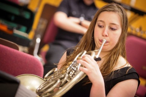 A female student plays the French horn.