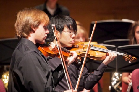 Two male students play the violin.