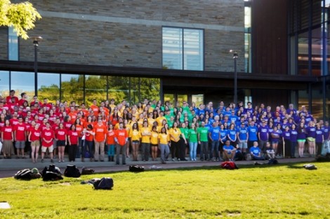 Dressed in t-shirts of multiple colors representing the rainbow/LGBTQ flag, students, faculty, and staff posed for a group photo on the steps of Skillman Library. 