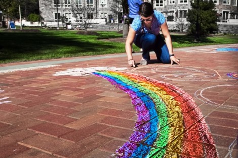 A student draws a chalk rainbow on one of the Quad's brick walkways during a Make a Wish Foundation program.
