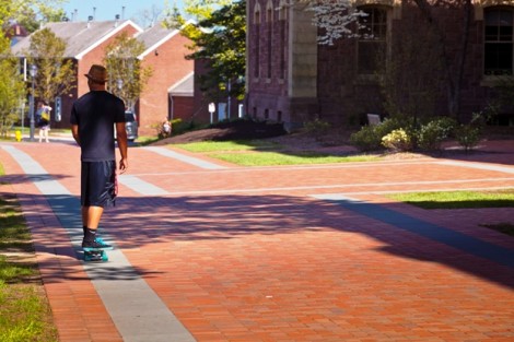 A skateboarder rides in front of Pardee Hall.