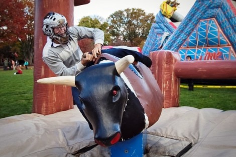 A student takes his turn trying to tame the mechanical bull.