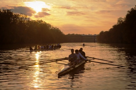 Members of the crew team practice on the Delaware River in the setting sun.