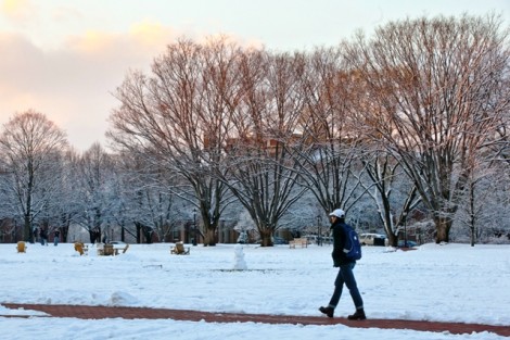 A student walks across the snow-covered Quad.