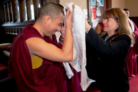 Marie Enea, assistant to the president, presents a monk with a white shawl as a symbolic gift of friendship.