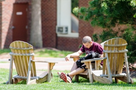 A student hangs out on an Adirondack chair on the Quad.