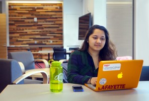 Nirupa Basnet ’17 takes advantage of one of the new study rooms. Wooden panels, like the one behind her, are featured throughout the building. The use of salvaged lumber from around the world in the center promotes local and recycled materials and reflects the global focus. 