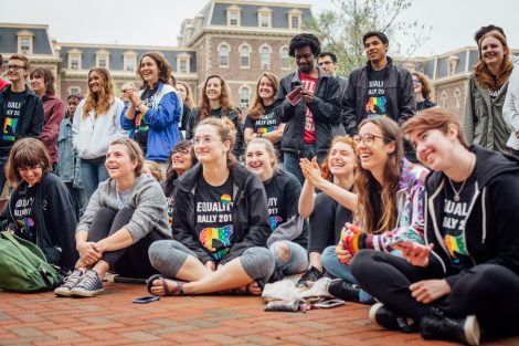 A group of students sits and listens to a speaker at the Equality Rally.