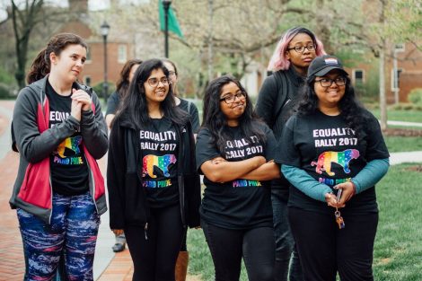 Several students wearing Equality Rally shirts smile and listen.