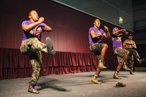 Men dancers perform and yell on stage