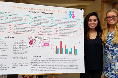 Two students stand by their research poster.