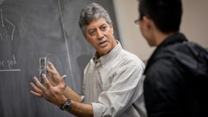 Math professor Gary Gordon teaches a student at a blackboard.