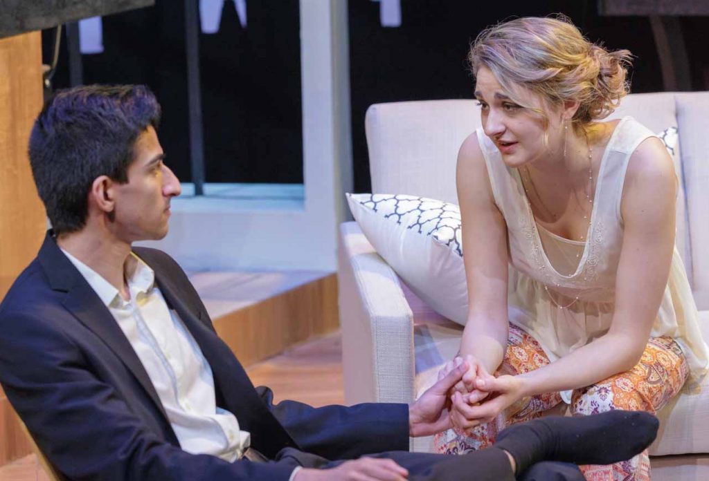 A male student and female student sit and talk while rehearsing the play Disgraced.